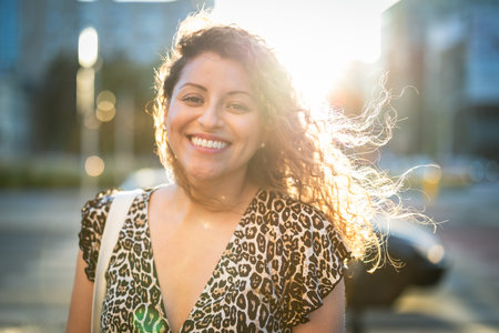 Portrait of a smiling young woman with curly hair in the cityの写真素材