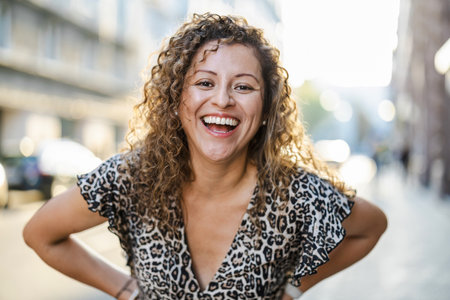 Portrait of a smiling young woman with curly hair in the cityの写真素材