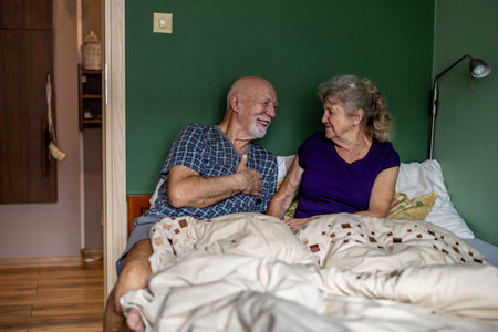 Elderly couple lying in bed and looking at each other with loveの写真素材