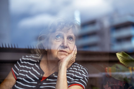 Portrait of senior woman looking through the window in the city.の写真素材