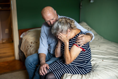 Sad senior couple sitting on the bed at home. Focus on manの写真素材