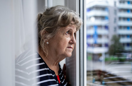 Portrait of an elderly woman standing by the window at home.の写真素材