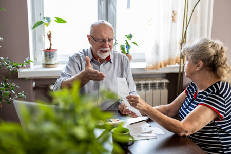 Elderly couple in the kitchen. Senior man and woman at the table with laptop.の写真素材