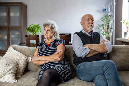 Senior couple sitting on sofa at home, looking at camera. Mature man and woman looking at camera.の写真素材