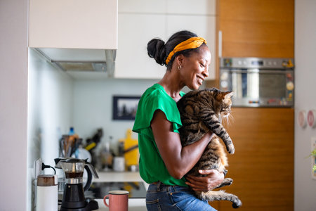 african american woman with her cat in the kitchen at homeの写真素材