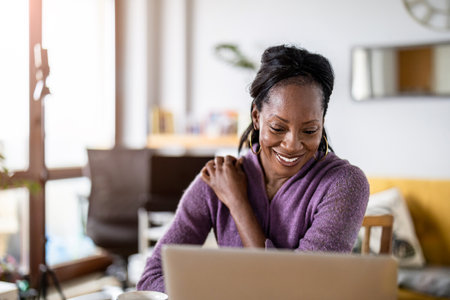 Portrait of smiling african american woman using laptop at homeの写真素材