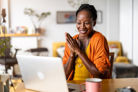 Portrait of smiling African woman using laptop while sitting at homeの写真素材