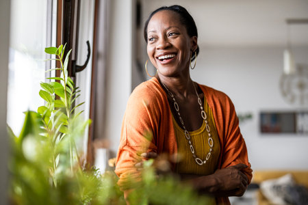 Portrait of smiling african american woman standing by window at homeの写真素材