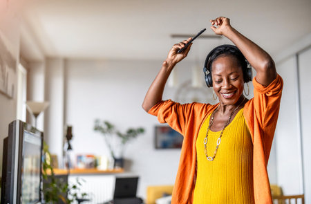 Portrait of smiling african american businesswoman listening to music with headphones in officeの写真素材