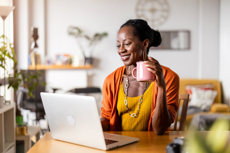 african american woman with cup of coffee and laptop at homeの写真素材