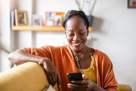 Portrait of smiling african american woman using mobile phone at homeの写真素材