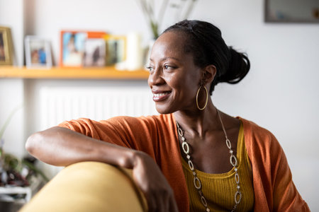 Portrait of smiling african american woman sitting on sofa at homeの写真素材