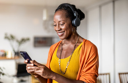 Portrait of smiling african american woman using mobile phone at homeの写真素材