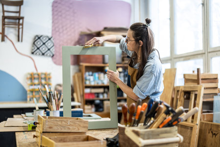 Young woman working in a workshop, she is using a wooden frameの写真素材