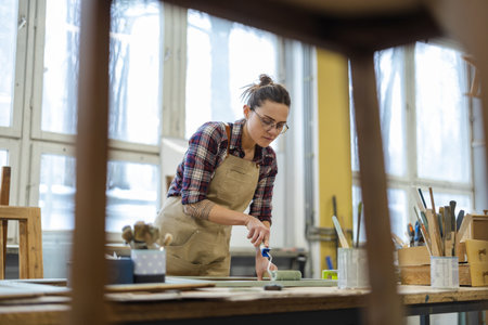 Female carpenter at work in her workshop. She is wearing glasses and apron.の写真素材