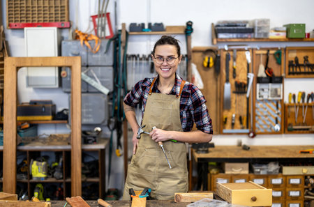 Portrait of young female carpenter in her workshop smiling at cameraの写真素材