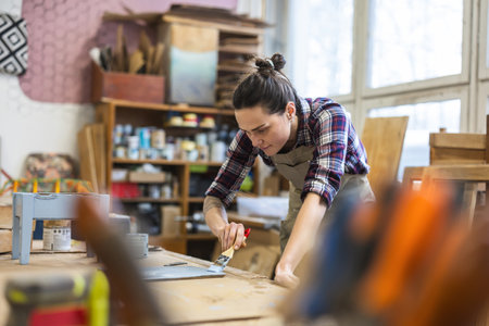 Female carpenter working on a wood in her workshopの写真素材