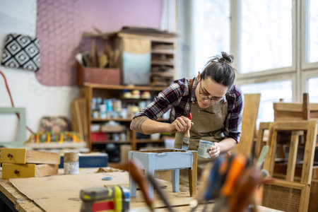 Female carpenter working on a wooden table in her workshop. Selective focus.の写真素材