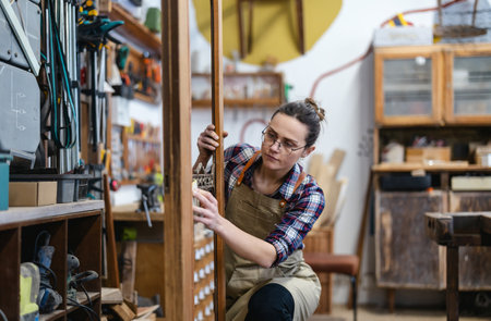 portrait of female craftsman in eyeglasses working in workshopの写真素材