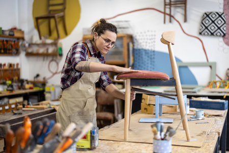 Portrait of a female craftsman working with a wooden chair in a workshopの写真素材