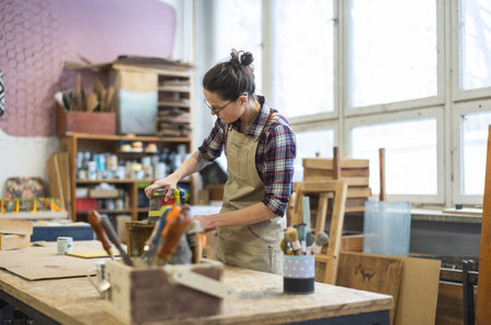 Portrait of a female carpenter working on a wooden table in her workshopの写真素材