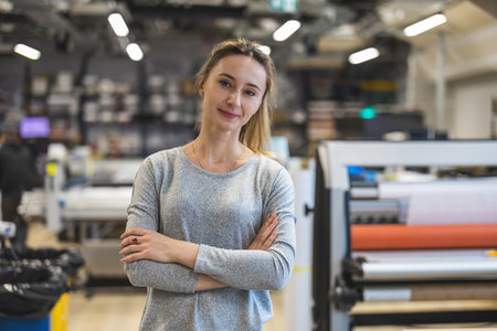 Portrait of confident female designer standing with arms crossed in printing studioの写真素材