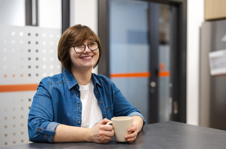 Portrait of a happy young woman holding a cup of coffee in a coffee shopの写真素材
