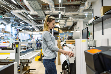 Female worker using a machine in a production line in a furniture factoryの写真素材