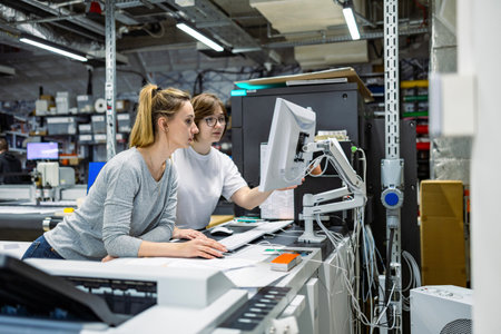 Two female engineers working on a computer at the computer lab in a factoryの写真素材
