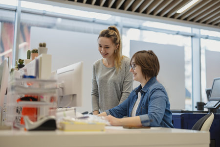 Portrait of two female colleagues working together at desk in creative officeの写真素材