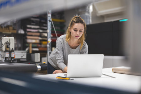 Portrait Of Female Factory Worker Working On Laptop In Modern Factoryの写真素材