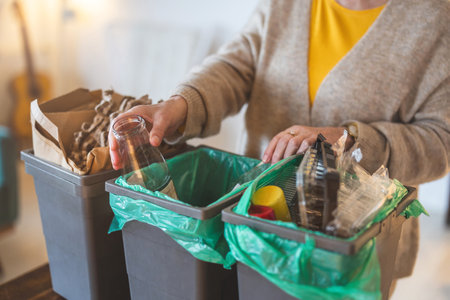 cropped shot of senior woman sorting garbage in recycling bin at home
