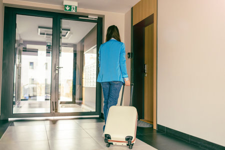 Young woman with a suitcase in the corridor of the hotel room.の写真素材