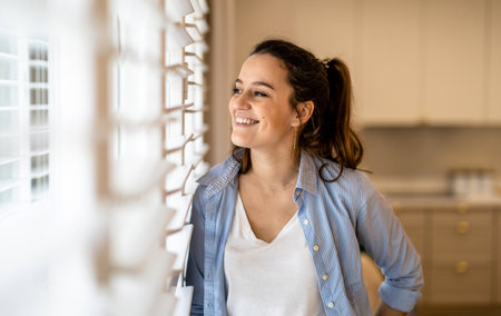 Portrait of a smiling young woman standing in the kitchen at homeの写真素材
