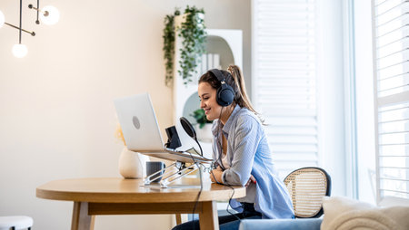 Young woman working at home with a laptop and headphonesの写真素材
