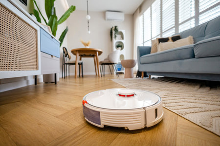 Robotic vacuum cleaner cleaning wooden floor in living room. House cleaning concept.の写真素材