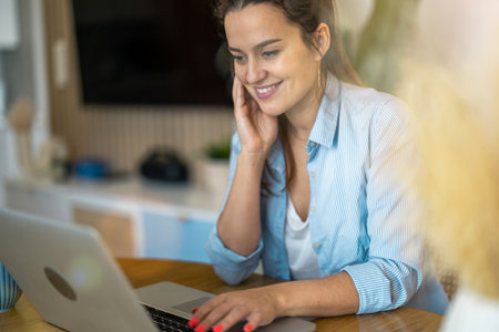 Portrait of smiling businesswoman working on laptop at desk in officeの写真素材