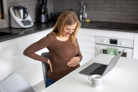Pregnant woman working with laptop at homeの写真素材