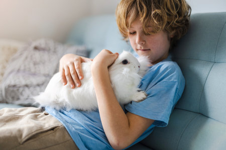 Cute little boy cuddling his bunny pet at homeの写真素材