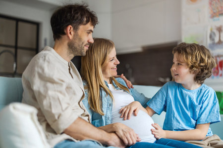 Pregnant woman with her husband and son in living room at homeの写真素材
