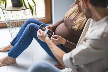 Pregnant woman sitting on the floor with her husband and holding a pregnancy test.の写真素材