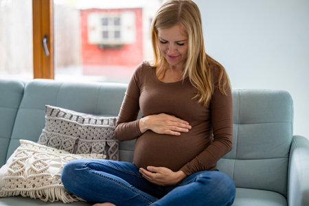 Pregnant woman sitting on sofa at home in the living roomの写真素材