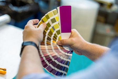 Close-up of a male worker holding a color palette in a factory