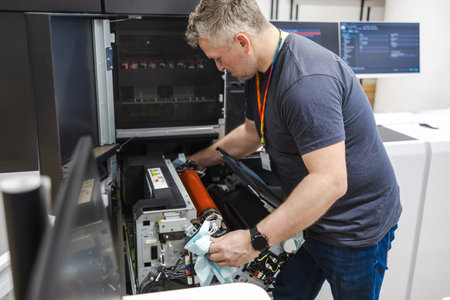 Technician at work in a printing studio, repairing a printer.の写真素材