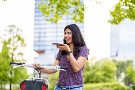 Portrait of a young woman with bicycle and mobile phone in the cityの写真素材