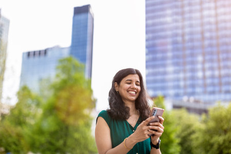Smiling businesswoman using mobile phone in the city with buildings in the backgroundの写真素材