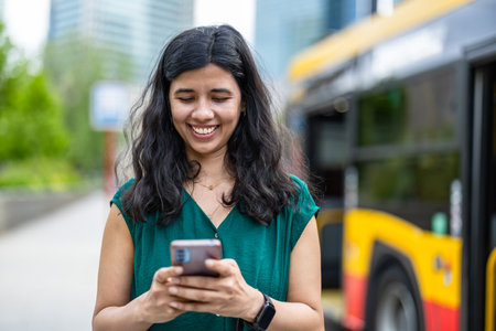 Portrait of happy young woman using mobile phone in the city.の写真素材
