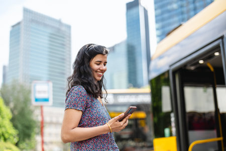 Portrait of a young woman using mobile phone in the city with busの写真素材