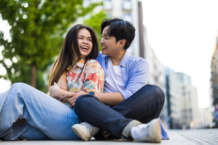 Young asian couple sitting on the street and looking at each otherの写真素材