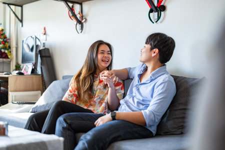 Young couple sitting on sofa and talking in living room at home.の写真素材